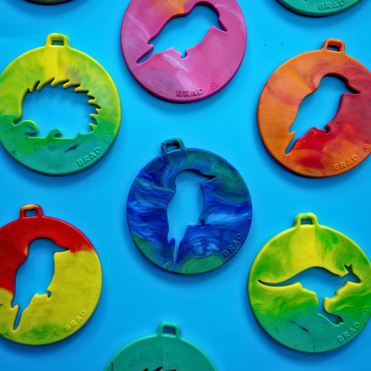 Recycled plastic echidna, kookaburra and kangaroo decorations in bright swirled colours laid out on a blue background.