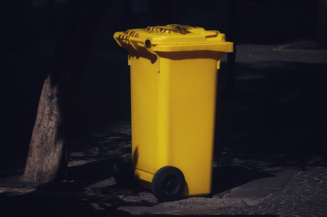 A yellow-lid kerbside recycling wheelie bin ready for collection