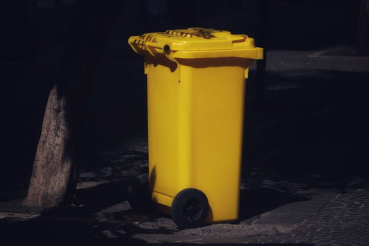 A yellow-lid kerbside recycling wheelie bin ready for collection