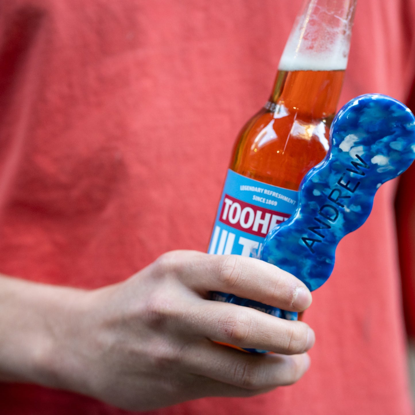 Deep Blue recycled bottle opener being used to open a bottle