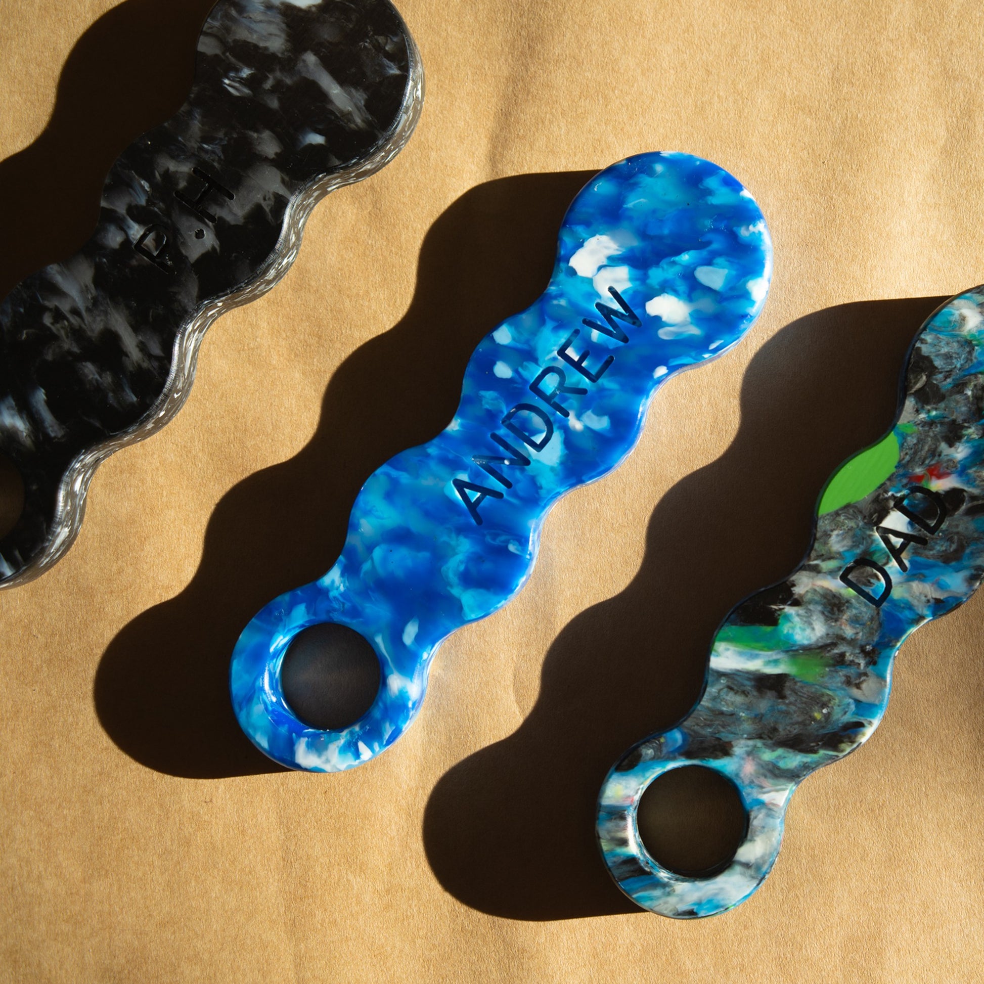 Three recycled bottle openers engraved with names, showing how personalisation looks