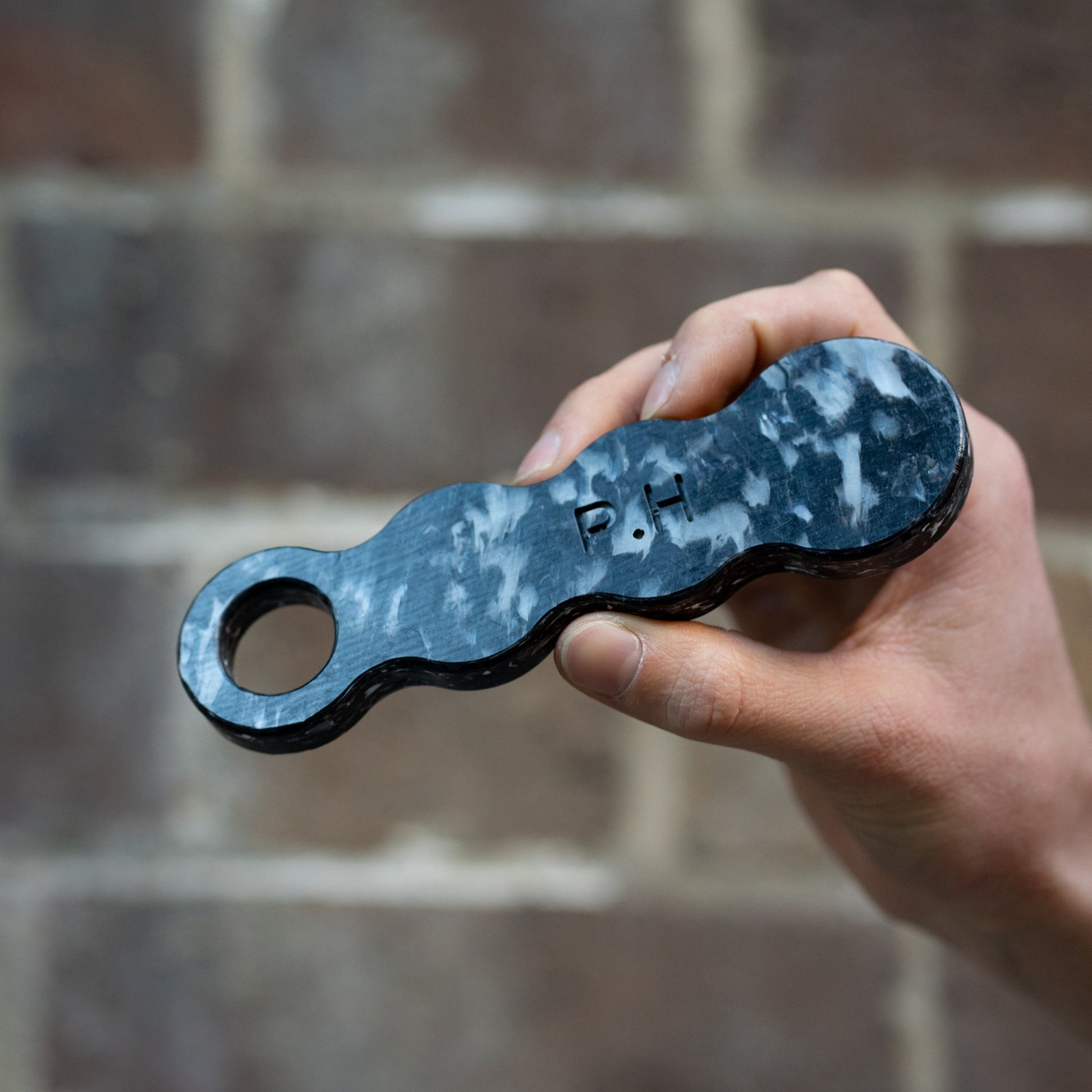 Midnight Black recycled bottle opener held in a hand with initials engraved on it