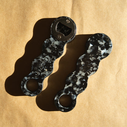 Two Midnight Black recycled bottle openers showing the black and white marbled pattern