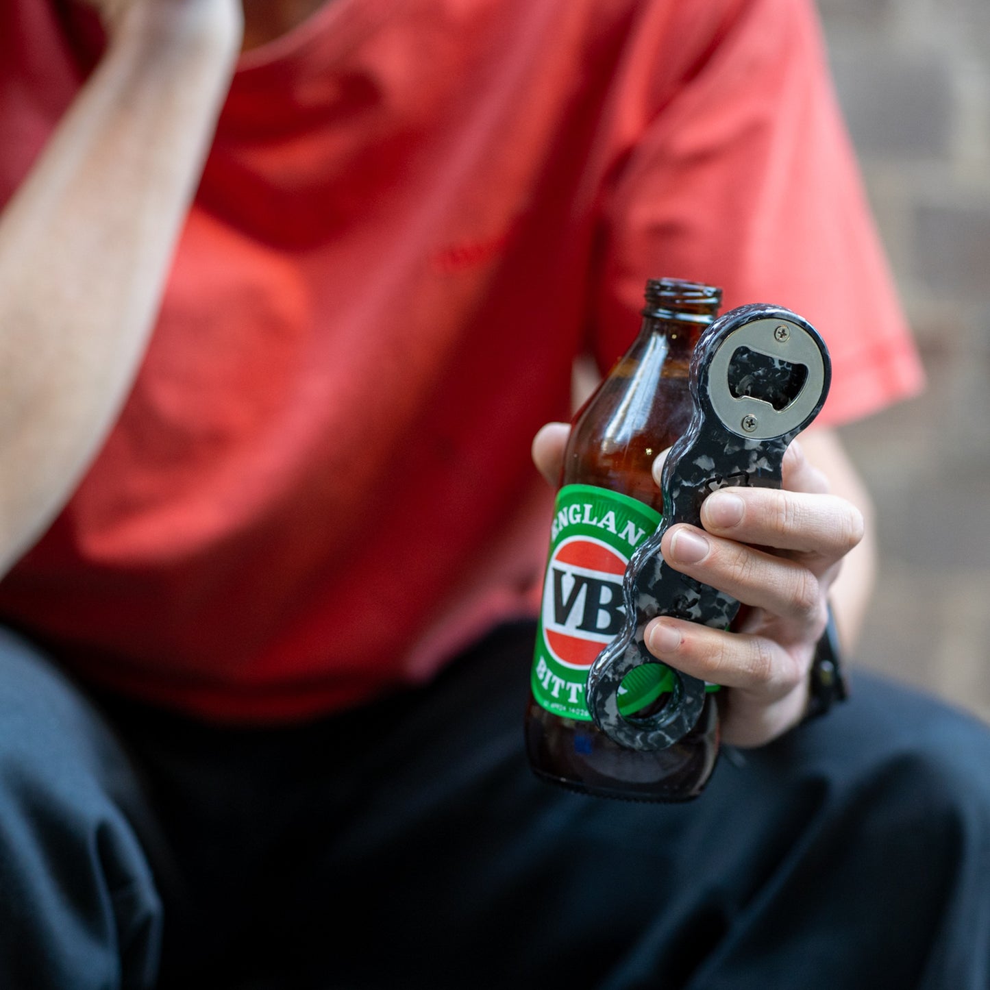 Midnight Black recycled bottle opener opening a beer bottle