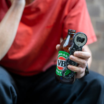 Midnight Black recycled bottle opener opening a beer bottle