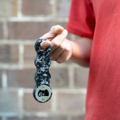 Midnight Black recycled plastic bottle opener hanging from a finger
