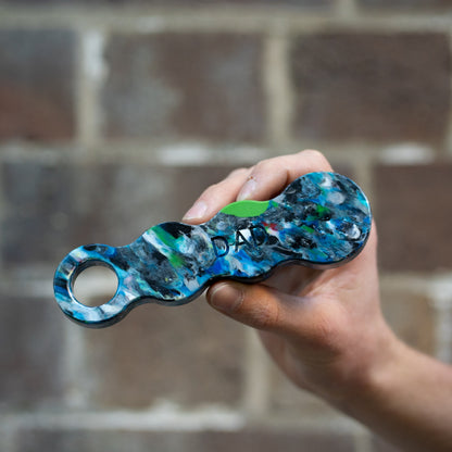 Orbital recycled plastic bottle opener held in a hand, engraved with DAD