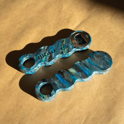 Two Orbital recycled bottle openers showing the swirled teal and grey pattern