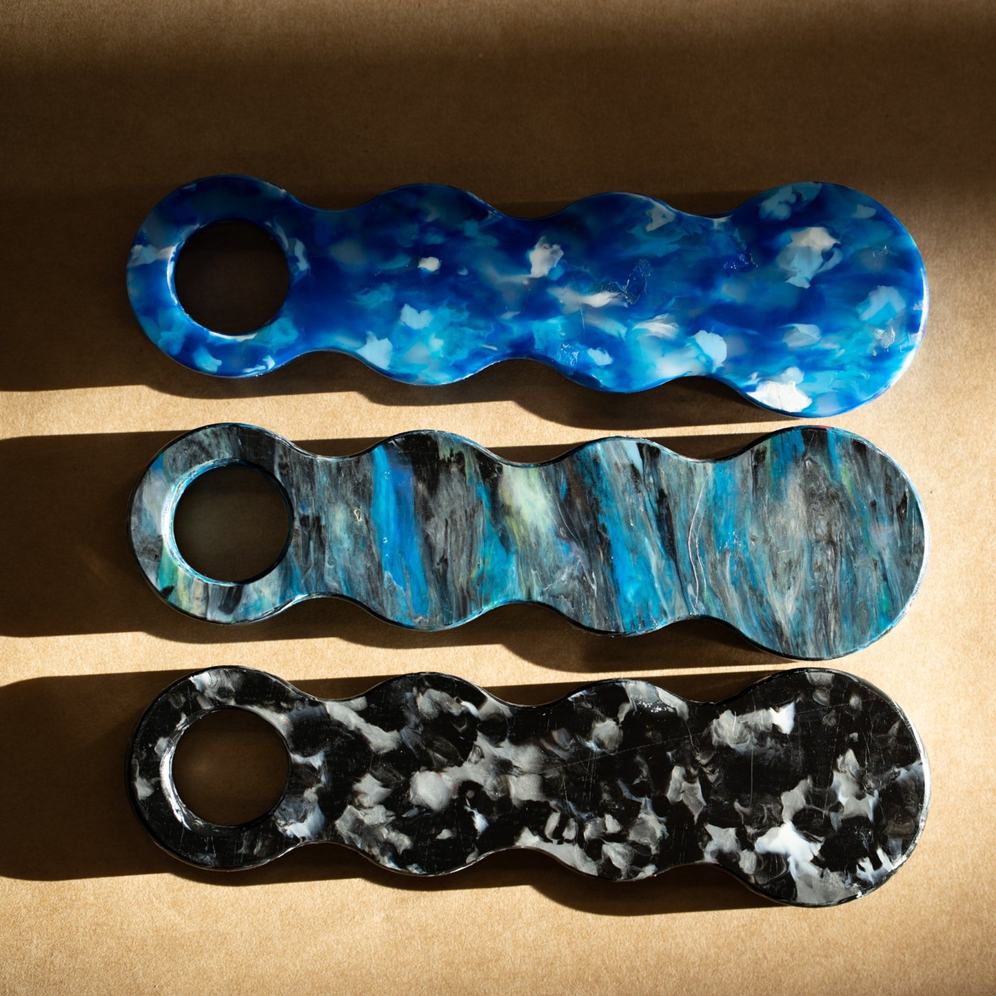 Three recycled plastic bottle openers in Deep Blue, Orbital and Midnight Black laid side by side