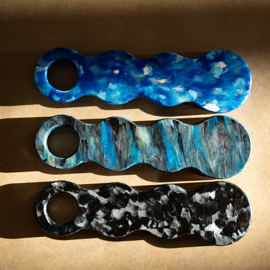 Three recycled plastic bottle openers in Deep Blue, Orbital and Midnight Black laid side by side